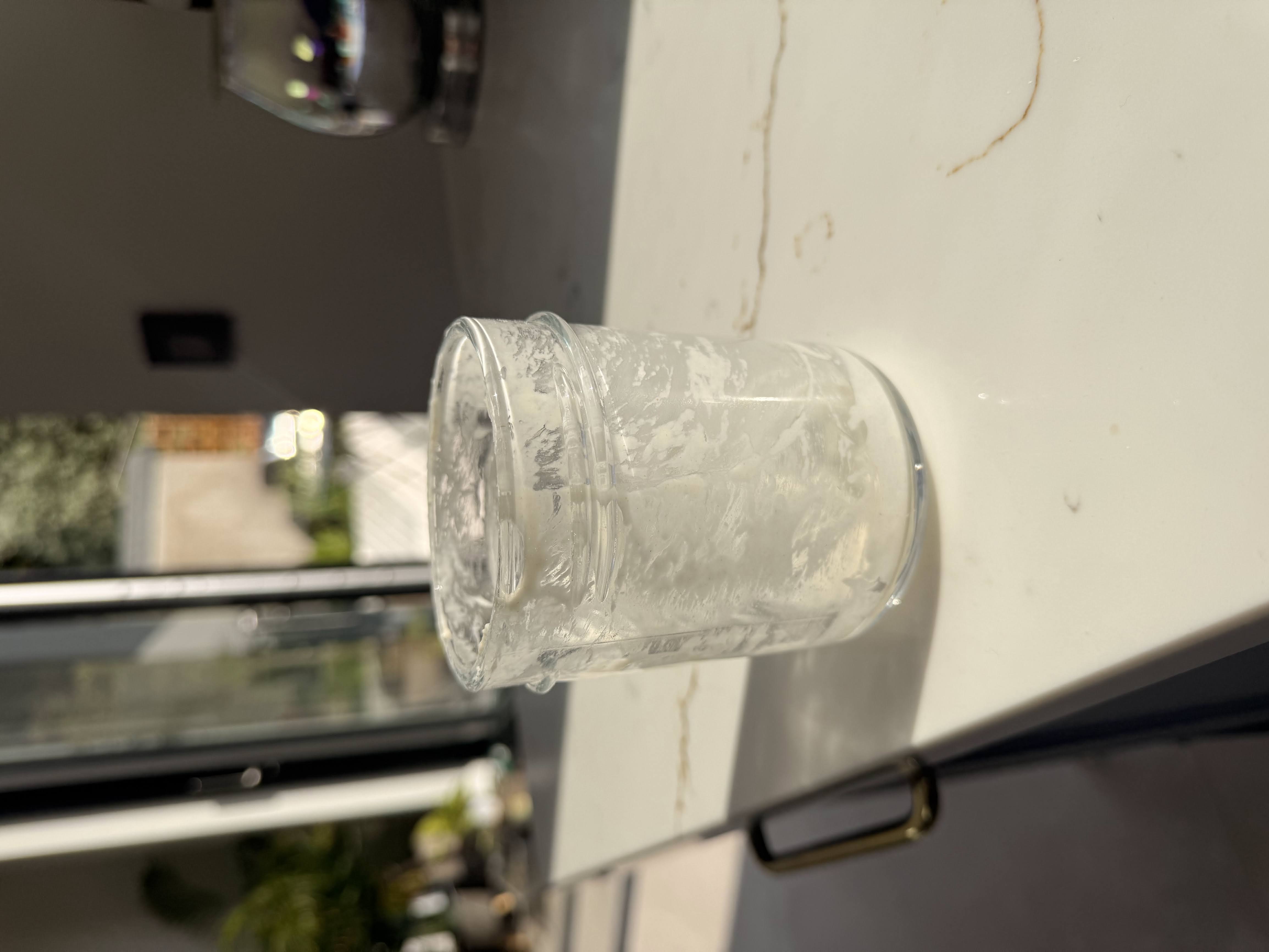 Glass jar showing small amount of sourdough starter scrapings ready for feeding