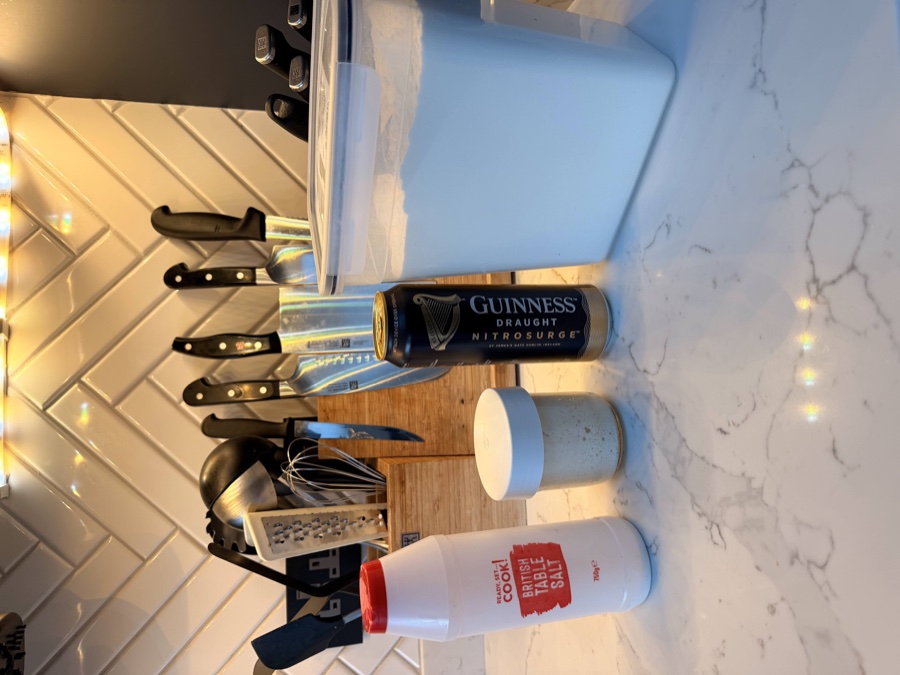The four ingredients for Guinness sourdough laid out: salt, sourdough starter, a can of Guinness Draught, and a container of flour